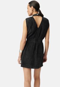 Abito in denim nero caratterizzato da un design senza maniche, una vita elastica e un'apertura sul retro. Il tessuto presenta un motivo a trama strutturata.