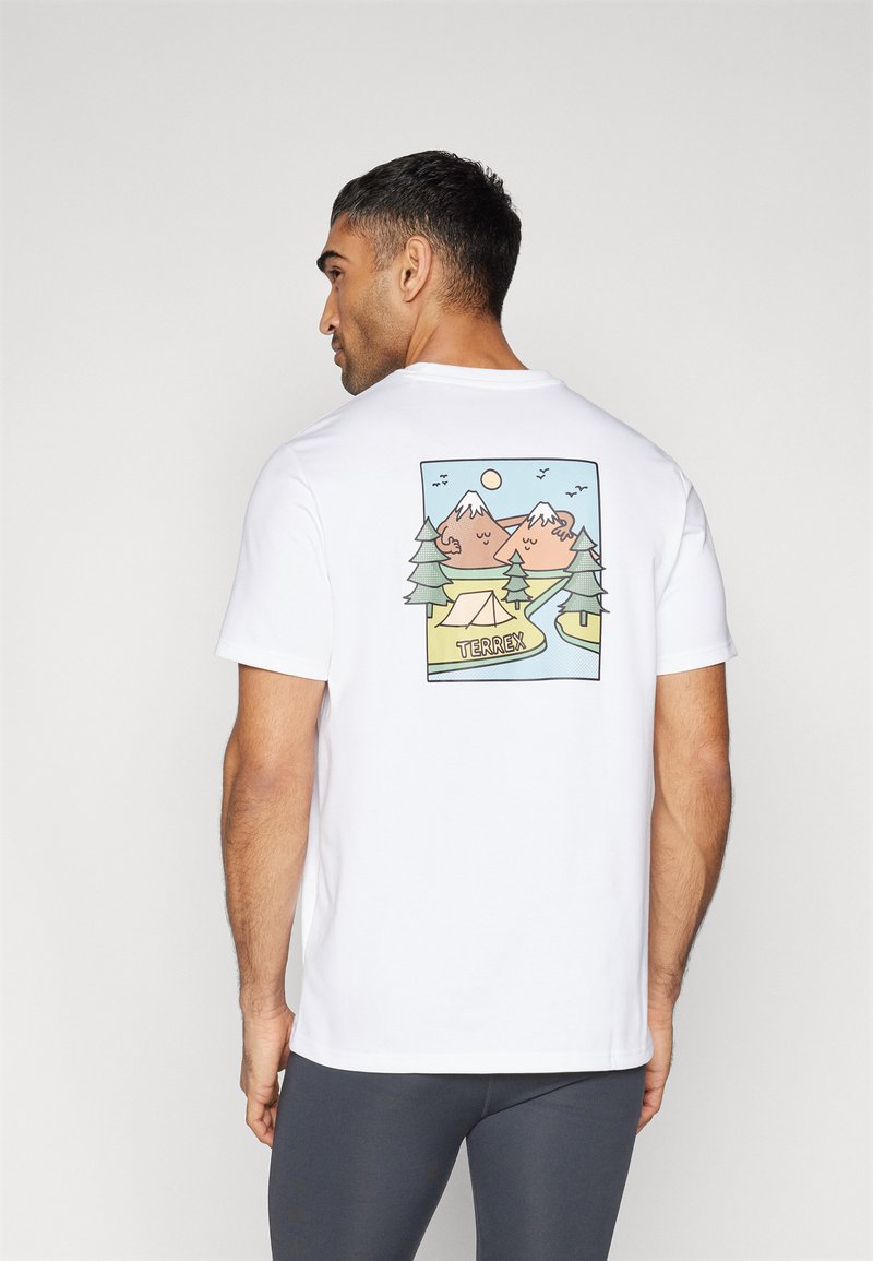 Camiseta blanca con un gráfico colorido de montañas, árboles y una tienda con el texto "TERREX" en la parte inferior, de mangas cortas y cuello redondo.