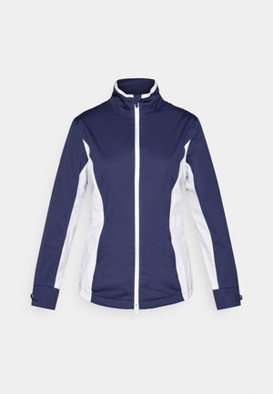 Chaqueta atlética azul marino con paneles laterales blancos, cremallera completa, cuello alzado y mangas largas. Fabricada con una tela ligera y suave.