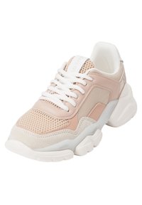 Chaussure de sport rose clair avec des panneaux en maille et en suède, dotée de lacets blancs et d'une semelle blanche épaisse. Marque discrète sur la languette.