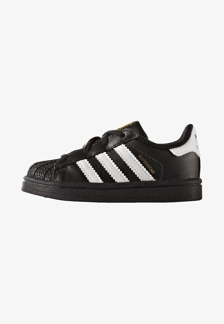 Black Adidas Superstar sneaker with white stripes, shell toe, and gold "Superstar" text on side, viewed from the outer side.