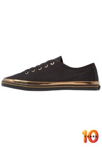 Schwarze Leinensneaker mit runder Zehenform, goldenen metallischen Details entlang der Sohle und schwarzem Gummiauslauf. Verfügt über fünf Ösen für Schnürsenkel.