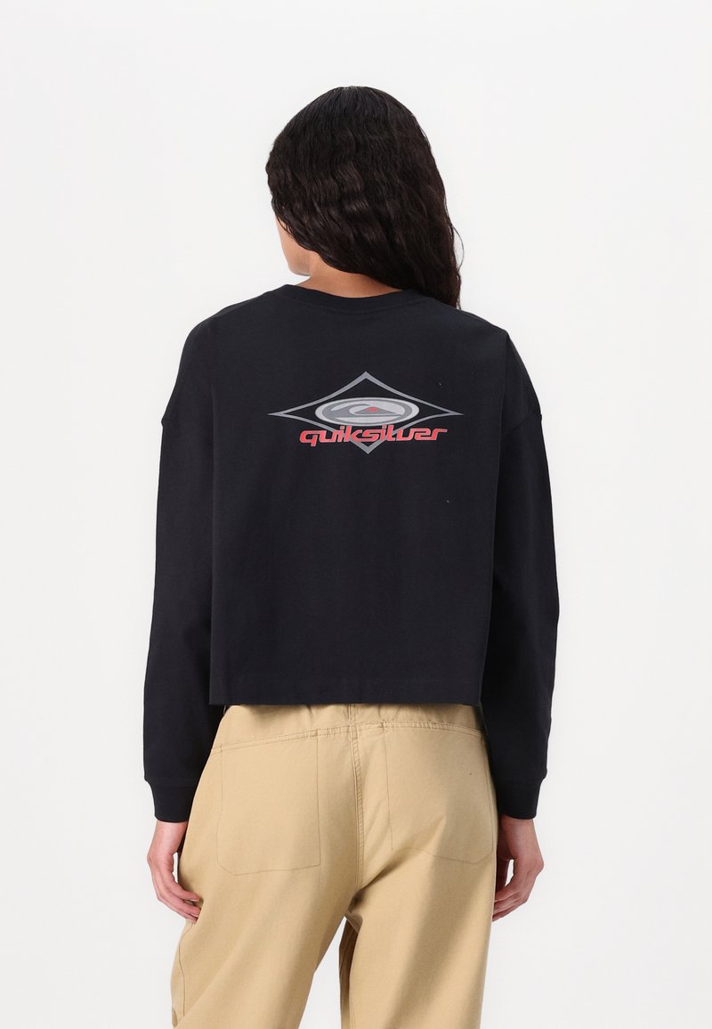 Sweatshirt court noir avec manches longues, arborant un logo Quiksilver argent et rouge dans le dos. Texture lisse, coupe décontractée, design minimal.