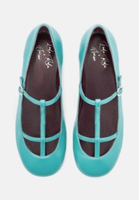 Ballerine in pelle turchese con punta arrotondata, dotate di un design a t-strap, dettaglio con fibbia argentata e fodera interna nera texturizzata.