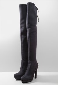 Stivali over-the-knee in suede nero con tacco alto, design affusolato, parte superiore elasticizzata e cordoncino per una vestibilità regolabile. Finitura texturizzata.