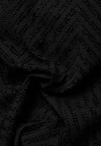 Svart texturerad tyg med en chevronmönster och upphöjda detaljer. Den mjuka texturen med varierande höjd skapar visuell djup.