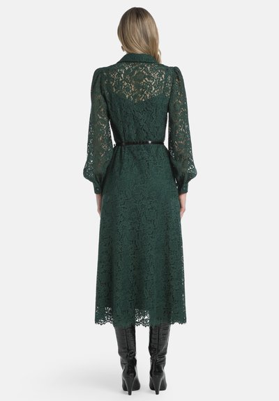 Grünes Spitzenkleid mit langen Puffärmeln, knielang und mit taillierter Passform. Verfügt über ein transparentes Spitzenmuster und einen schwarzen Gürtelakzent.