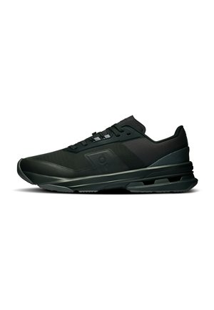 Sneaker sportiva nera low-top con suola texturizzata, chiusura con lacci e branding discreto sul lato, mostrata di profilo su sfondo bianco.