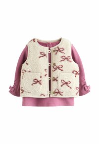 Fleece-Weste in Creme mit pinkem Schleifenmuster, Vorder-Taschen und Druckknopfverschluss, über einem pinken, gerippten Langarm-Top mit gerafften Ärmeln getragen.