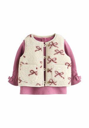 Fleece vest i creme med lyserødt båndmønster, forlommer og trykknaplukninger, lagdelt over en lyserød ribbet bluse med lange ærmer og sammenfoldede ærmer.