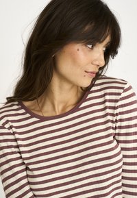 Langærmet top i creme med maroon vandrette striber, ribbet tekstur og rund halsudskæring, der har en afslappet pasform og blødt stof.
