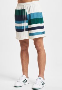 Uimalahkeet kermaan, joissa vaakasuorat raidat tummansinisen, petroolin ja valkoisen sävyissä. Venyvä vyötärönauha nyörillä ja sivutaskut.