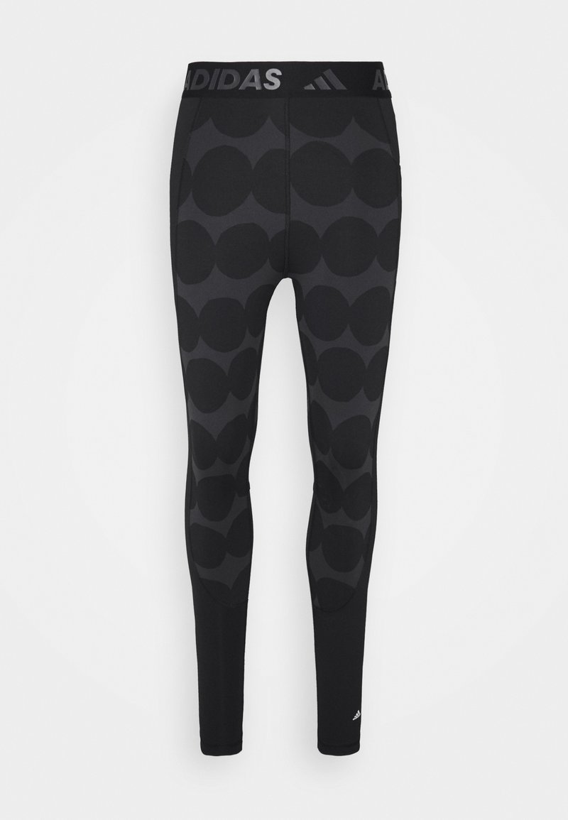 Black athletic leggings featuring a large polka dot pattern, stretchy fabric, a wide waistband with the Adidas logo, and a slim fit.