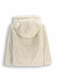 Kremowy sztuczny futrzany płaszcz z kapturem, który ma małe uszy misia. Miękka faktura, widoczne szwy z przodu i z boku. Brak zapięć.
