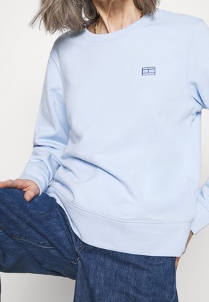 Sudadera de corte crewneck en azul claro, fabricada con un tejido suave, que presenta un pequeño logo bordado en el pecho y puños y dobladillo acanalados.