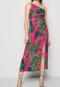 Růžové bezramínkové šaty s asymetrickým výstřihem a řasením. Obsahují potisk zelených tropických listů a boční rozparek.