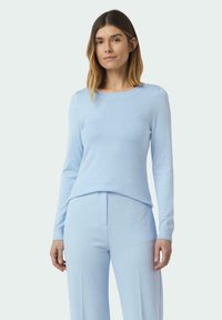 Helles blaues, gestricktes Sweatshirt mit langen Ärmeln und rundem Ausschnitt, kombiniert mit passenden hellblauen Hosen. Glatte Textur, taillierte Passform.