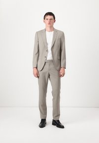 Blazer e calças de fato cinza claro, combinados com uma t-shirt branca. O fato tem um corte slim e uma textura suave, complementado por sapatos pretos.