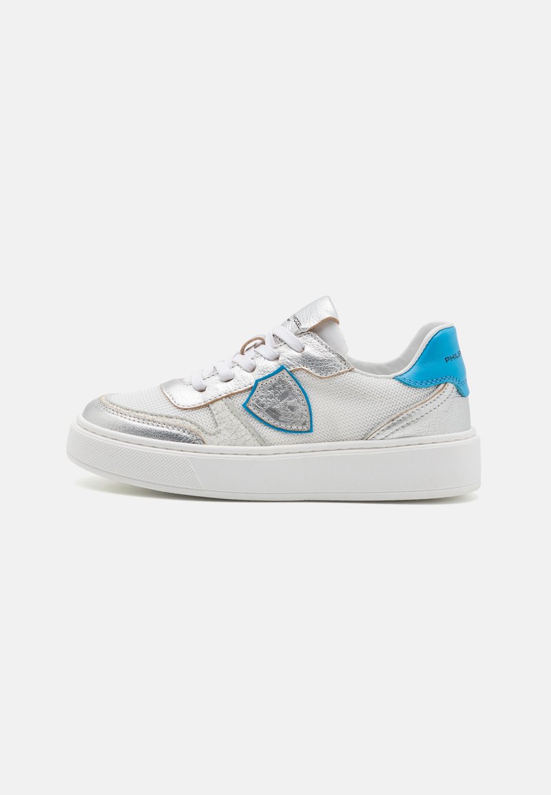 Weißer Textilsneaker mit silbernen Akzenten, einer blauen Fersenschlaufe und einem strukturierten blauen Dekorelement. Runde Zehenpartie mit weißer Sohle.
