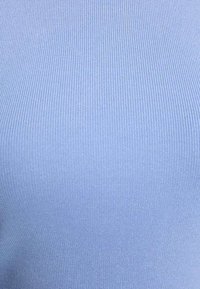 Primer plano de tela azul claro acanalada que muestra líneas texturizadas verticales.