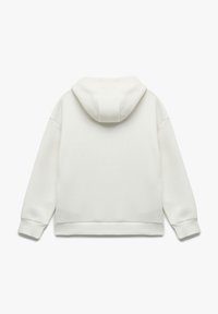 Vit hoodie med en mjuk textur, avslappnad passform och manschetterade ärmar. Har en enkel, minimalistisk design utan synlig branding.