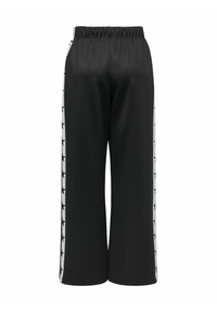 Pantalones de pierna ancha negros con cinturilla elástica, que presentan franjas laterales blancas adornadas con patrones de estrellas negras. Tela suave y ligera.