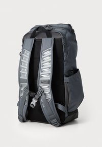Zaino grigio con schienale e spallacci imbottiti. Presenta dettagli riflettenti e cinturini regolabili. Tasca laterale visibile.