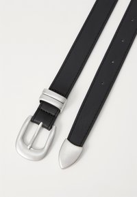 Ceinture en cuir noir avec une boucle rectangulaire en argent et un embout pointu. Présente des coutures le long des bords et plusieurs trous pour l'ajustement.