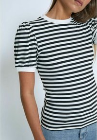 Svītrains melnbalts īsām piedurknēm tops, pieguļošs dizains ar ribotu tekstūru, ar pūkainām piedurknēm un apaļu kakla izgriezumu.