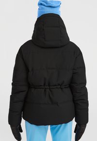 Sort polstret jakke med hætte, indsnævret talje og sidelommer. Tekstureret stof og quiltet design forbedrer isoleringen. Blå hue synlig ovenfor.