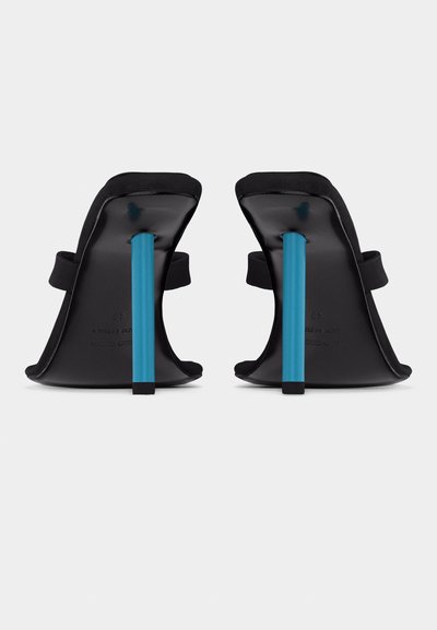 Μαύρα σανδάλια με ψηλό τακούνι και φαρδιές λωρίδες, με λεπτά στιλέτο τακούνια σε έντονο μπλε χρώμα, εμφανιζόμενα από πίσω σε απλό φόντο.