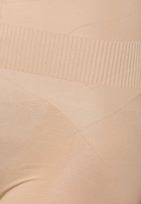 Beige shaping tights with a ribbed waistband, smooth texture, and seamless design showing varying patterns and thickness for support.