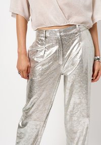 Zilver metallic broeken met een glanzende textuur, hoge tailleband, geplooide voorkant en rechte pijp. Wrijf- en reflecterende oppervlakte details.