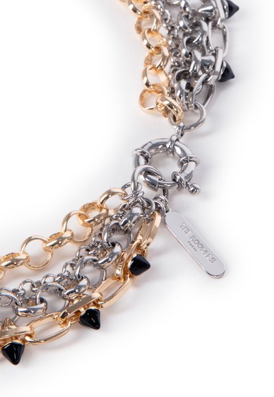 Kædearmbånd med vekslende guld- og sølvled, pyntet med sorte kegleformede perler og et metallisk mærke graveret med "THE KOOPLES."