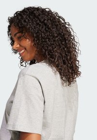 Siva pamučna majica kratkih rukava s opuštenim krojem i okruglim izrezom. Vidljiva tekstura i meki izgled tkanine.