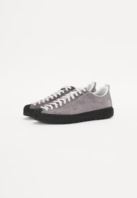 Graue Wildledersneaker mit weißen Schnürsenkeln und einer schwarzen Gummisohle. Mit einer runden Zehenpartie und einem Logo nahe der Ferse. Leicht strukturiertes Obermaterial.