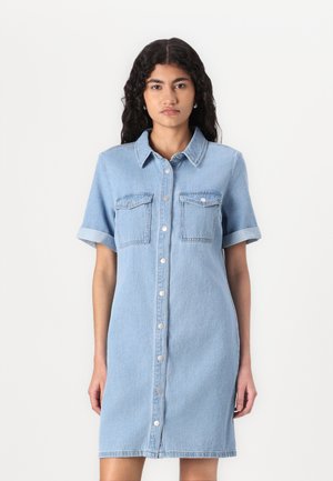 Light blue denim dress with short sleeves, button-down front, and two chest pockets. Soft texture, knee-length cut, and rolled sleeve cuffs.