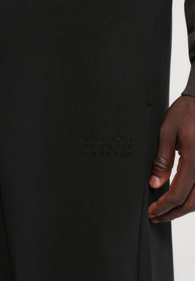Black, lightweight fabric pants with a clean design. Features a side pocket and embossed numbering detail near the pocket area.