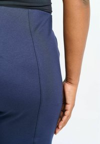 Marineblauwe high-waisted legging met een gladde textuur, voorzien van een zijnaaddetail en een aansluitend ontwerp. Ideaal voor sportkleding.