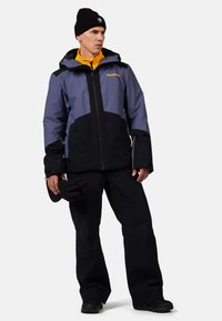Blau- und schwarze wasserdichte Jacke mit Kapuze, ausgestattet mit einem gelben Innenfutter und Branding auf der Brust. Schwarze Hose und Handschuhe sind enthalten.