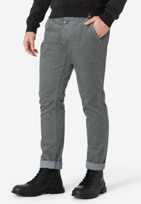 Grijze ribfluweelbroek met een slim fit, voorzien van voorzakken en opgerolde manchetten. Gepaard met zwarte veterschoenen van het type combat.