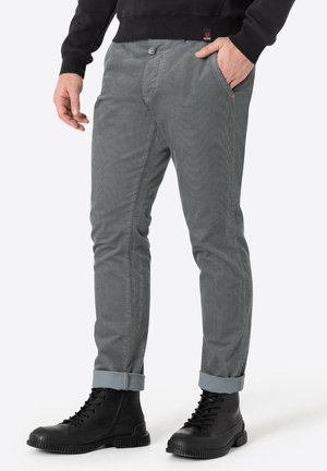 Graue Cordhosen mit slim Fit, ausgestattet mit Vordertaschen und umgeschlagenen Säumen. Kombiniert mit schwarzen Schnürkampfstiefeln.