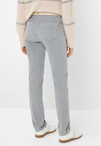 Grau Cordhosen mit Gesäßtaschen, gerade geschnitten, kombiniert mit weißen Turnschuhen. Der Stoff hat eine weiche Textur und einen dezenten Glanz.
