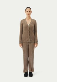 Brun ribbad stickad cardigan med knappstängning, som matchas med ribbade byxor. Båda är tillverkade av mjukt material med en avslappnad passform.