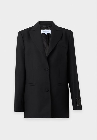 Μαύρο tailored σακάκι με λοξές πέτες, δύο εμπρόσθια κουμπιά, πλαϊνές τσέπες και μια μικρή ετικέτα στο μανσέτα του δεξιού μανικιού.