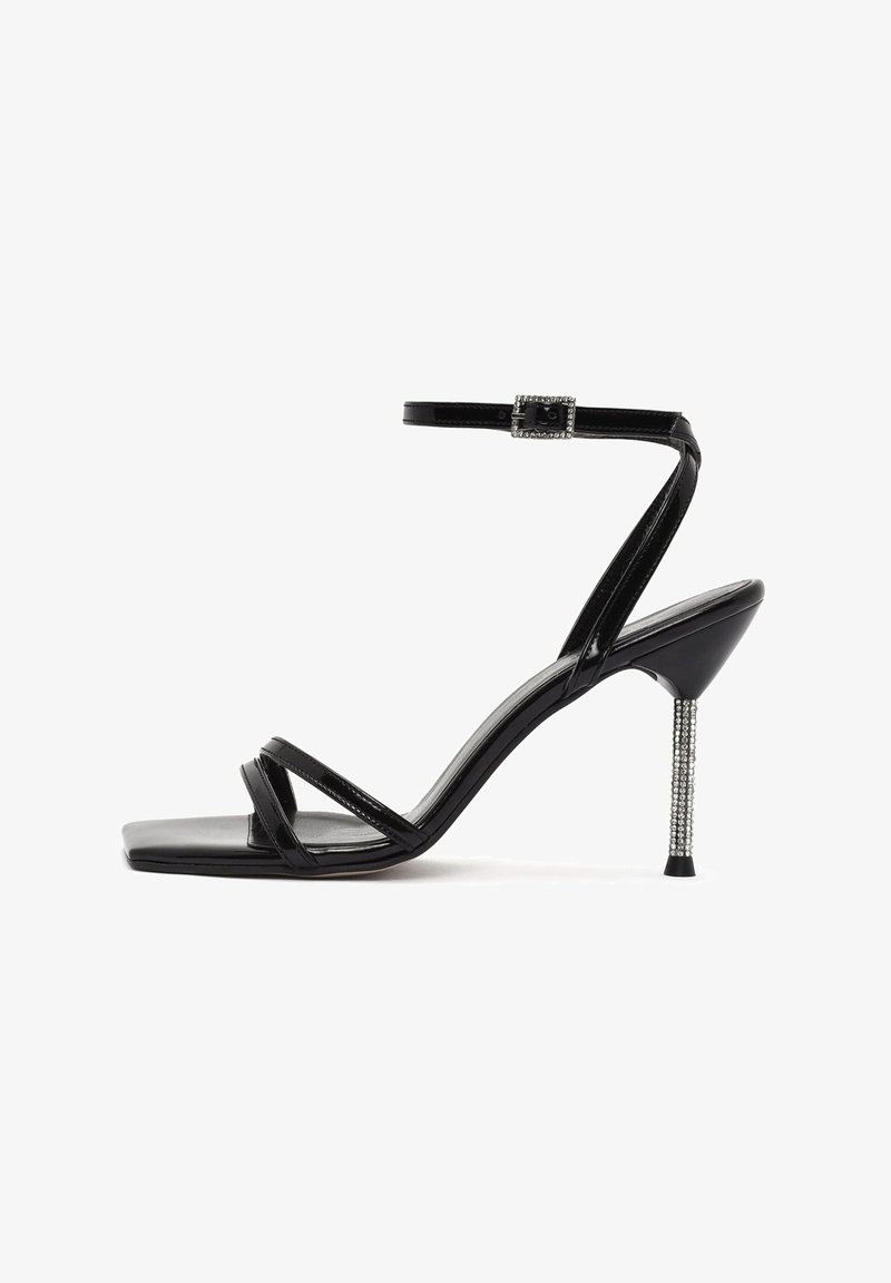 Zwarte gepatenteerde leren sandalen met een vierkante neus, meerdere slanke banden en een stiletto hak versierd met strass steentjes. Verstelbare enkelband.