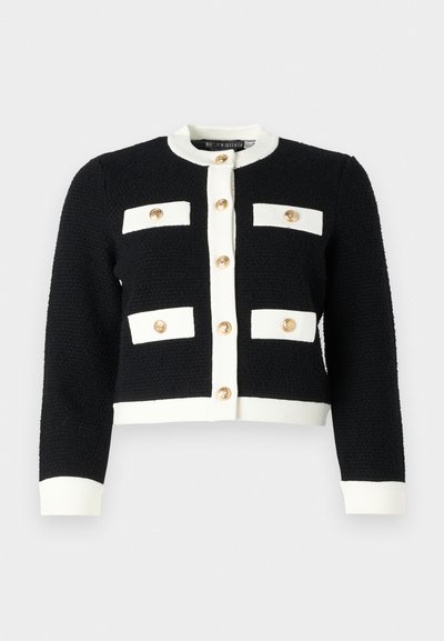 Pulover scurt alb-negru din țesătură texturată, având patru buzunare frontale și nasturi aurii pe centru.