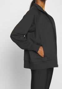 Svart zip-up sweatshirt med hög krage, ribbade manschetter och sidofickor. Tillverkad av mjukt tyg, som erbjuder en avslappnad passform och modern design.