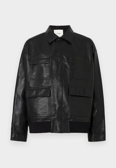 Giubbotto in pelle sintetica nera con colletto, chiusura frontale a bottoni automatici, bordo a costine e quattro grandi tasche a pattina e a toppa sul davanti.