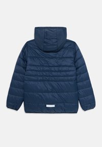 Veste rembourrée bleu marine avec un matelassage horizontal, des poignets élastiques, une capuche et un petit patch réfléchissant rectangulaire dans le bas du dos.